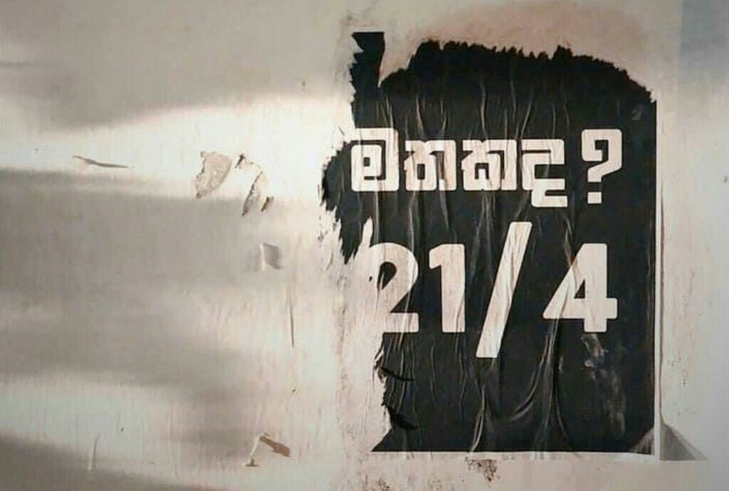 A torn black poster on a white wall, that reads ‘mathakada 21/4?’ or ‘remember 21/4?’. Photograph by Thyagi Ruwanpathirana.