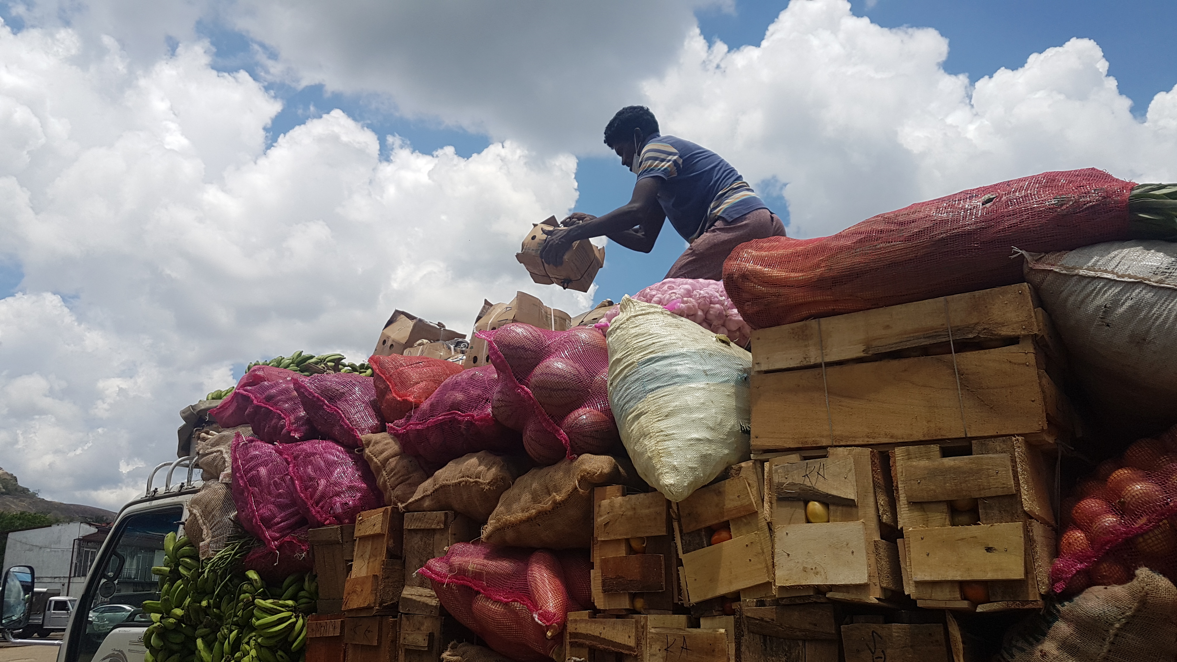 A man loads boxes and sacks laden with produce into a lorry leaving the Dambulla market, most likely for another market outside the city.
